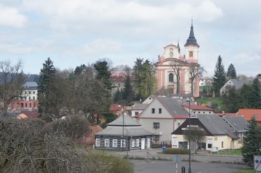 Obr. 1 – Kostel s klášterem (vlevo za stromy) a opravenou budovou č. 2 (zcela vlevo) nad městem Nová Paka
