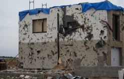 Ukázka působení rychle letících projektilů zaražených do stěn poničené budovy (Zdroj: Souhrnná zpráva ČHMÚ)