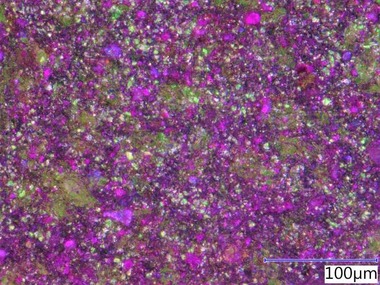 Obr. 6: Fotografie z optického mikroskopu, B) Kompozit s jemným grafitem B, zvětšení 1 000× (zelená barva = grafit, fialová = silikátová matrice)