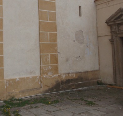 Obr. 10: Vlhkostní klín na obvodové stěně kostela v koutě u sousedního objektu souvisí s masivním shromažďováním dešťové vody u paty zdiva