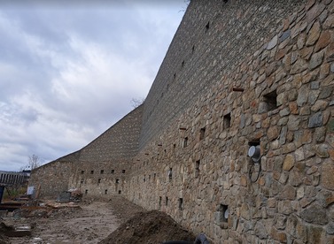 Obr. 5b – Pohľad na západnú časť OM1 (možno vidieť nosníky s 5-lanovými kotvami, nosníky s 19-lanovými kotvami, tyče WR 47 osadené pred líc múru, vylamováky pre kvetináče, odvodńovacie otvory fi 70 mm, v pozadí geodrenážna fólia medzi torkrétom a žb. stenou)